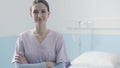 Young nurse posing next to a hospital bed