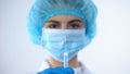 Young nurse preparing syringe with vaccine, pumping out air bubbles, healthcare