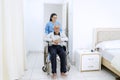 Young nurse pushing wheelchair of old man Royalty Free Stock Photo