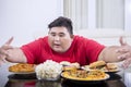 Young obese man looks tempted to eat lots of food