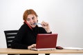 Young office worker woman talking on a cell phone sitting behind working desk with laptop computer and notebook Royalty Free Stock Photo