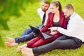 Young office workers with bare feet sit on a green lawn with a l