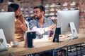 Blurred faces of young man and woman colleagues talking in front of table with desktop computer, in clothing store Royalty Free Stock Photo