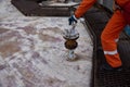 Young offshore engineer sounding fuel oil cargo tank on cargo deck on supply vessel in harbor.