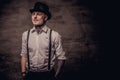 Young old-fashioned tattooed guy wearing a white shirt with suspenders and cylinder hat, looking at a camera. Royalty Free Stock Photo