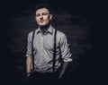 Young old-fashioned tattooed guy wearing white shirt and suspenders, looking at a camera on a dark background. Royalty Free Stock Photo