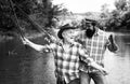 Young and old fisherman standing on the shore of lake with fishing rod. Father and son enjoy life. Men family, granddad Royalty Free Stock Photo