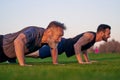 The young and old men push up together on the grass. Royalty Free Stock Photo