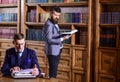 Young oldfashioned writer with typewriter in library with bearded friend