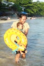 Toddler boy carried by mom to sea on beach Royalty Free Stock Photo