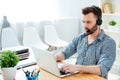 Young operator of call center with head-phones work with laptop