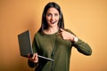 Young operator woman with blue eyes working on call center using computer laptop and headset with surprise face pointing finger to Royalty Free Stock Photo