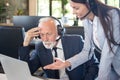 Young operator woman showing to her senior colleague how to solve problem on laptop at office. Royalty Free Stock Photo