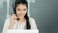 Young operator woman touching microphone on headset and working with smile and doing customer support at work in telemarketing Royalty Free Stock Photo