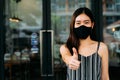 Young optimistic Asian female student giving thumbs up gesture. She`s wearing a protective mask PPE to avoid air