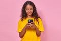 Young optimistic Indian woman uses phone to chat with friends stands in studio Royalty Free Stock Photo