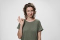 Young optimistic woman with curly hair demonstrates okay sign