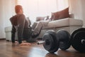 Young ordinary man go in for sport at home. Hardworking beginner sit on floor and hold legs on sofa. Freshmen trying to Royalty Free Stock Photo