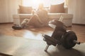 Young ordinary man go in for sport at home. Regular guy sit at sofa on floor after hard workout. Has rest and drink Royalty Free Stock Photo