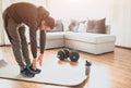 Young ordinary man go in for sport at home. Stand on mat and stretch down to toes. Ordinary guy warming out body before