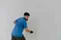 A young oriental man paints a wall with a roller. Royalty Free Stock Photo