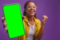 Young overjoyed African American woman holds out phone with green screen Royalty Free Stock Photo
