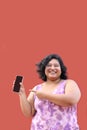 Young overweight brunette Latin woman of 20 years old shows the screen of her cell phone very happy about promotions and discounts