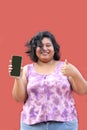 Young overweight brunette Latin woman of 20 years old shows the screen of her cell phone very happy about promotions and discounts