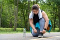 Young overweight woman stops to tie her shoe during her morning exercise run at running track of a local park