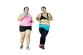 Young overweight women jogging together in studio