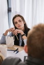 young overworked manageress sitting at workplace with box of chinese food Royalty Free Stock Photo