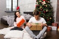 Young pair in pajamas unpacking their presents while sitting on Royalty Free Stock Photo