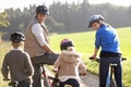 Young parents with children ride bikes in park Royalty Free Stock Photo