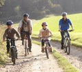 Young parents with children ride bikes in park Royalty Free Stock Photo