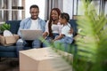 Young parents with daughter sitting on sofa and using laptop Royalty Free Stock Photo