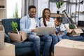 Young parents with daughter sitting on sofa and using laptop Royalty Free Stock Photo