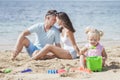 young parents embrace each other as their little daughter playing sand toys Royalty Free Stock Photo