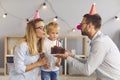 Young parents giving birthday cake to their shy little son during quiet celebration at home Royalty Free Stock Photo