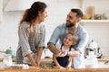 Young parents have fun baking with little daughter