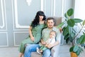 Young parents hug their baby in a bright room in green clothes, happy family concept, family Day Royalty Free Stock Photo