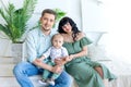 Young parents hug their baby in a bright room in green clothes, happy family concept, family Day Royalty Free Stock Photo