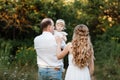 Young parents hugging each other and holding on the hands their little smiling daughter. Concept on family holidays and walking at Royalty Free Stock Photo