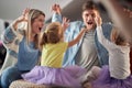 Young parents imitating monsters with their little daughters at home. Family, home, playing