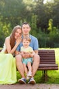 Young parents with little girl on bench in park Royalty Free Stock Photo