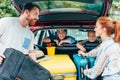 young parents packing luggage in trunk of car with kids