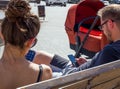 Young parents sit on the Olympic Park bench with phones in their hands