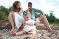Young parents sitting in thoughts on the sand beach. A small baby playing in front. Royalty Free Stock Photo