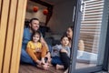 Young parents and small children sit on floor of living room at home in front of open panoramic window Royalty Free Stock Photo