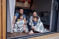 Young parents and small children sit on floor of living room at home in front of open panoramic window Royalty Free Stock Photo