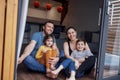 Young parents and small children sit on floor of living room at home in front of open panoramic window Royalty Free Stock Photo